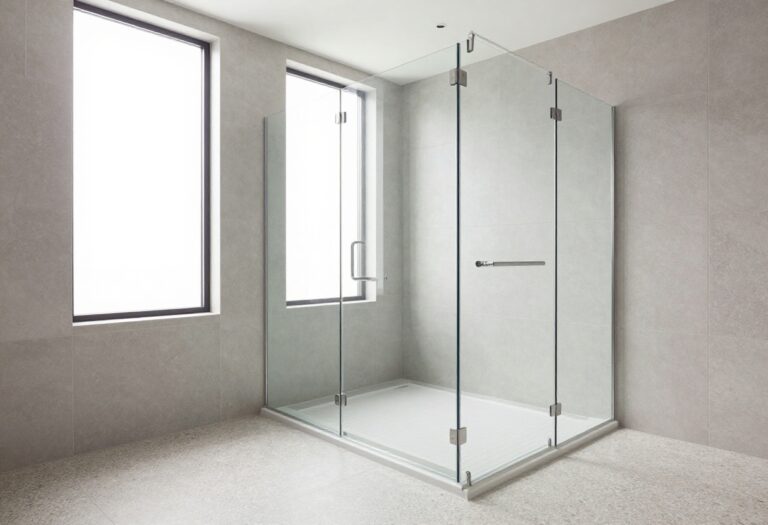 Modern curbless shower with light gray tiles, glass partition, and natural light in a polished bathroom setting.