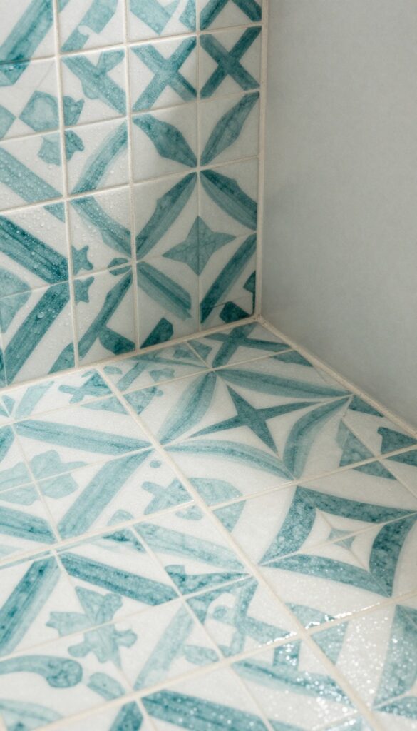 Close-up photograph of a patterned ceramic tile shower threshold in a bright, clean bathroom, featuring geometric designs for visual interest without text or overlay.