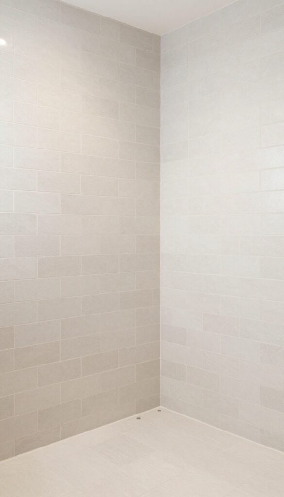 Photorealistic standing shower with floor-to-ceiling tile in natural light, showcasing clean design and architectural detail for bathroom inspiration.
