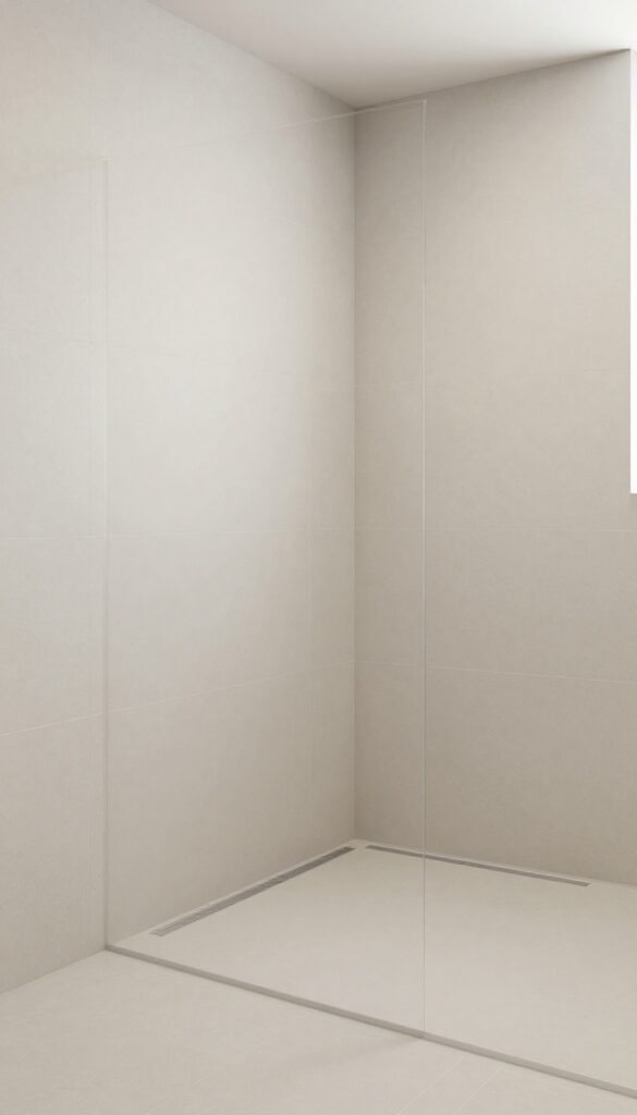 A curbless shower with a linear drain along the wall, featuring large neutral tiles and a sleek, polished bathroom design.