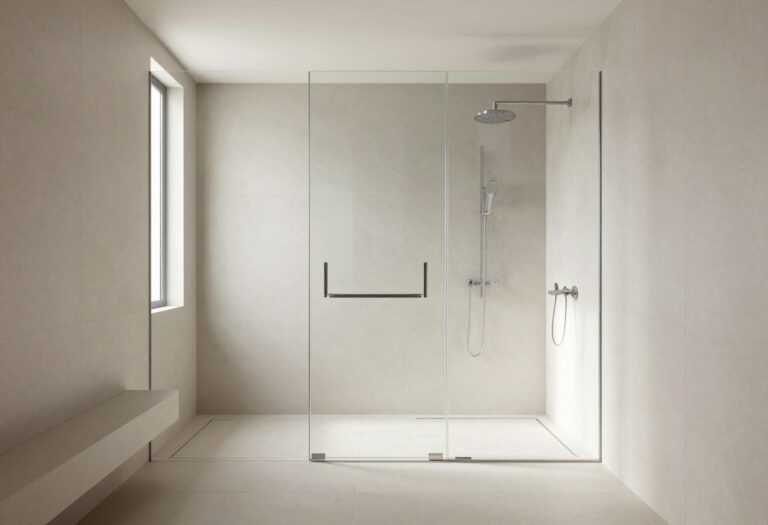 Modern bathroom with frameless glass shower, large tiles, rainfall showerhead, and built-in bench in a bright, polished setting.