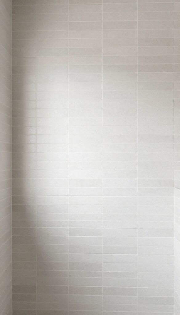 Vertical stacked tile pattern in a master bathroom shower creating an airy and elegant look with clean lines and natural light.