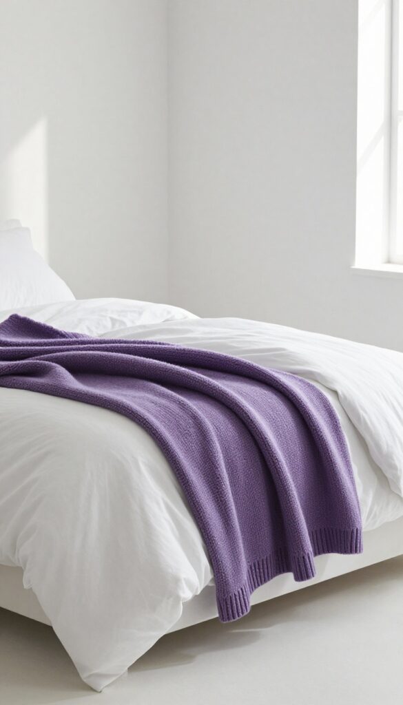 White bed with layered purple throw blankets in a bright, airy bedroom
