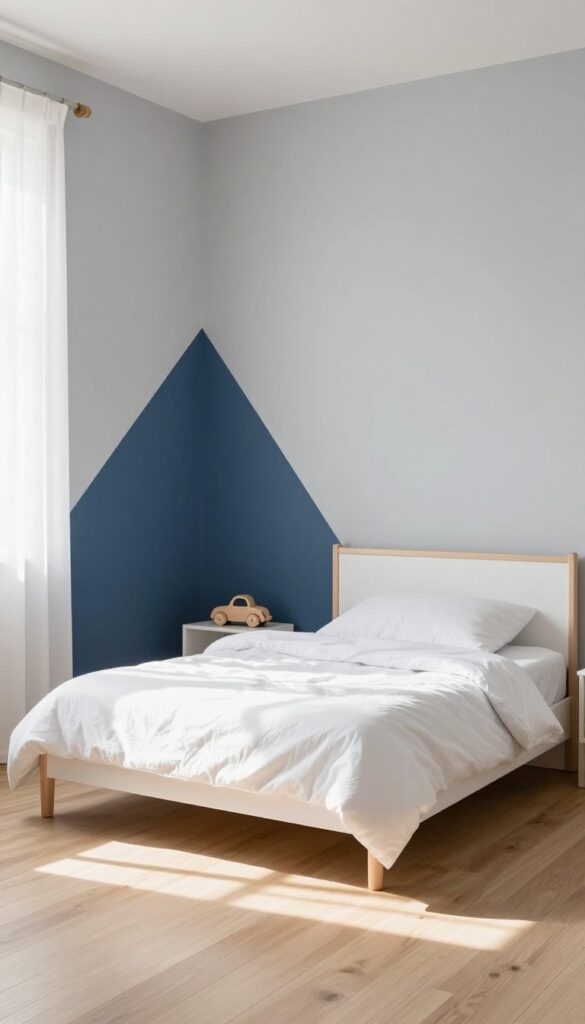 A little boy's bedroom with a navy blue accent wall, white bedding, and natural wood furniture in bright natural light.