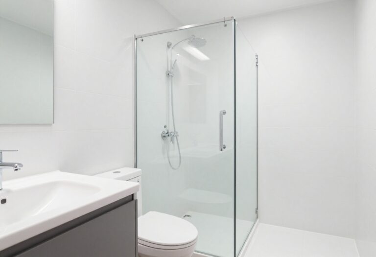 Clean and organized bathroom with white tiles and glass shower door