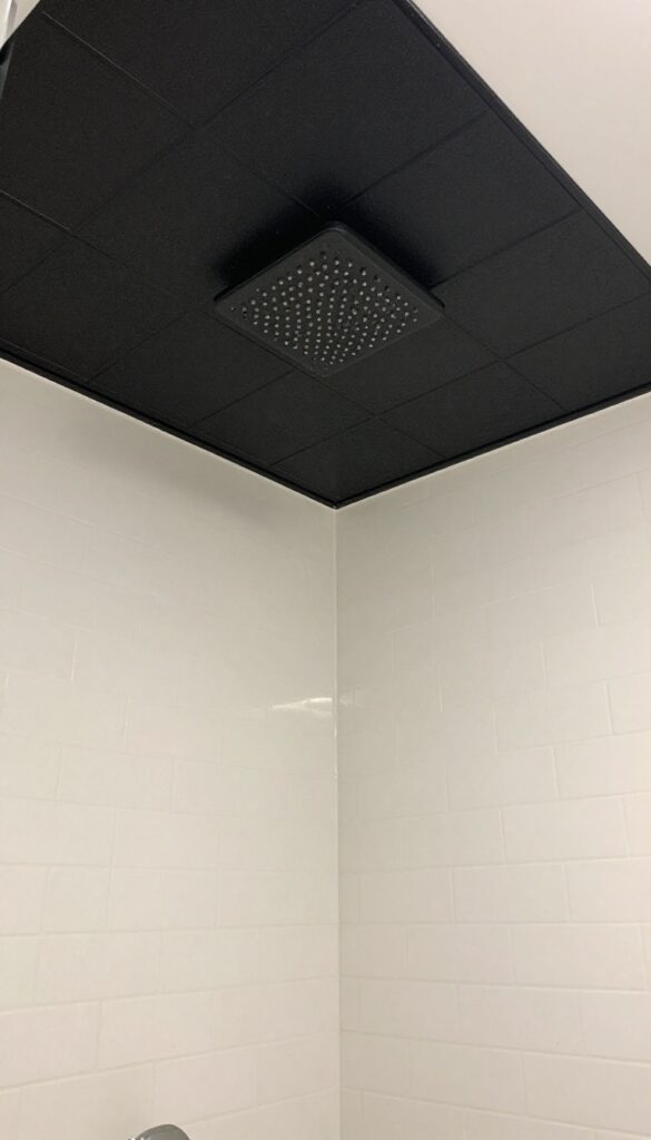 Black tile ceiling in a modern shower with white walls and recessed lighting