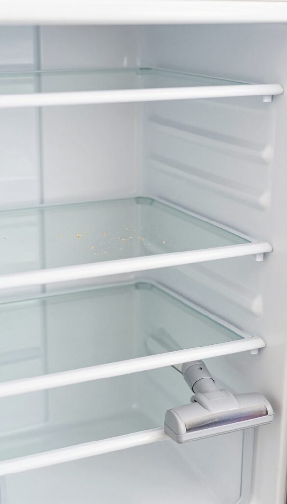 Vacuum crevice tool cleaning crumbs from refrigerator drawer track