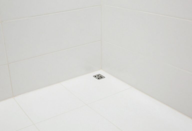 A clean, sparkling shower floor with white tiles and light grout.